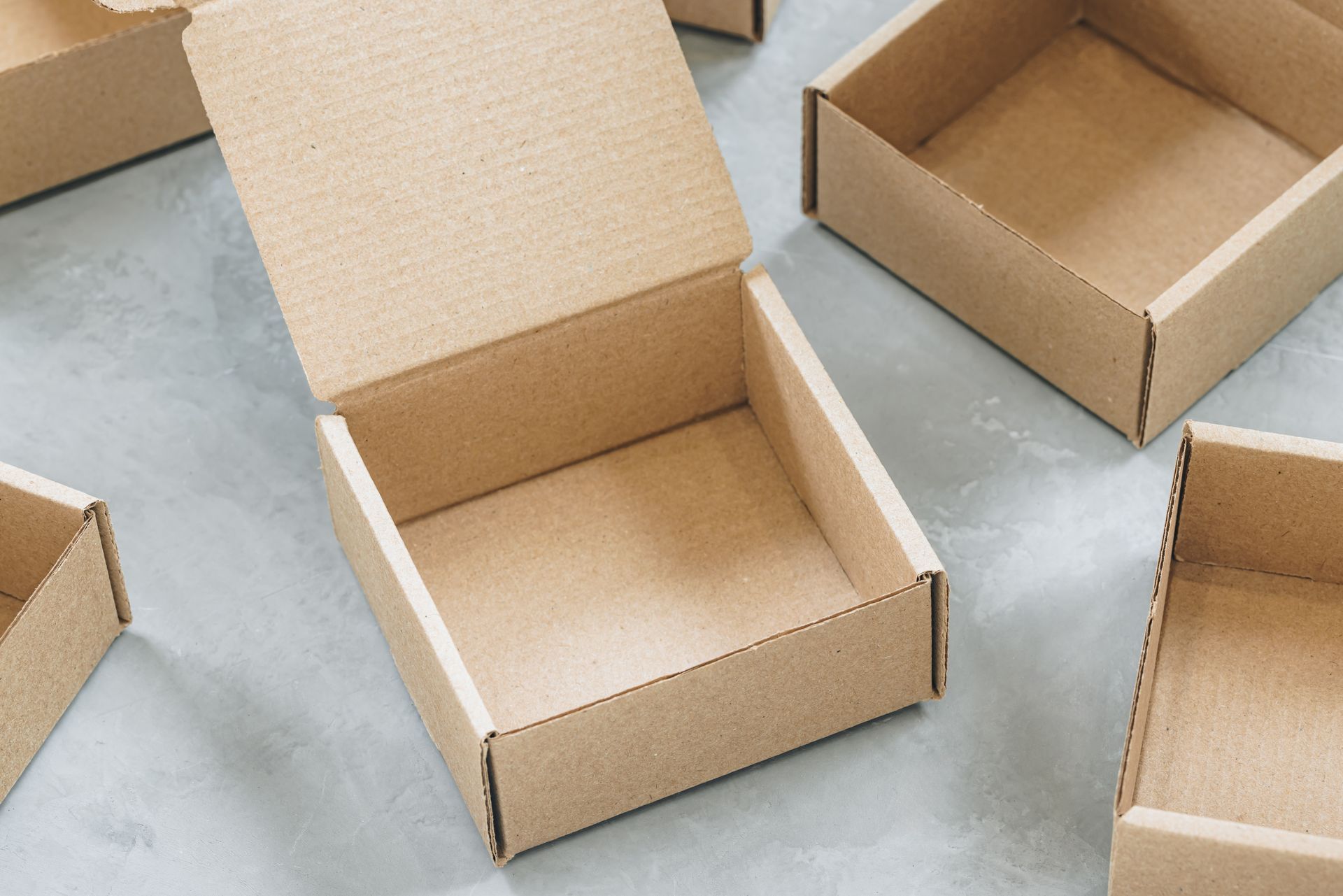 Open cardboard boxes on a gray surface, some with flaps open.