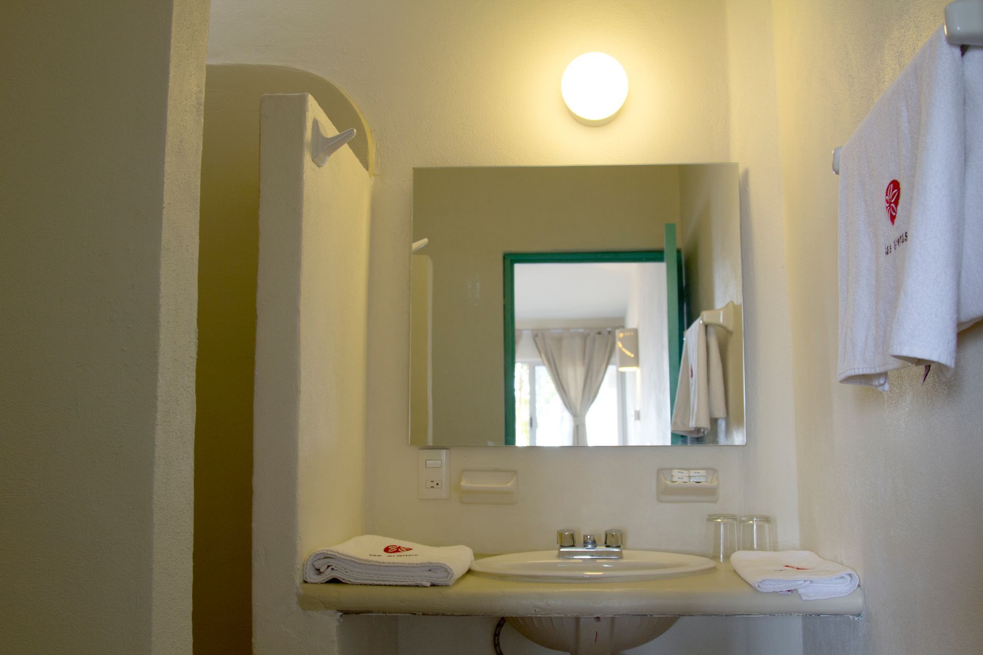 A bathroom with a sink , mirror and towels.