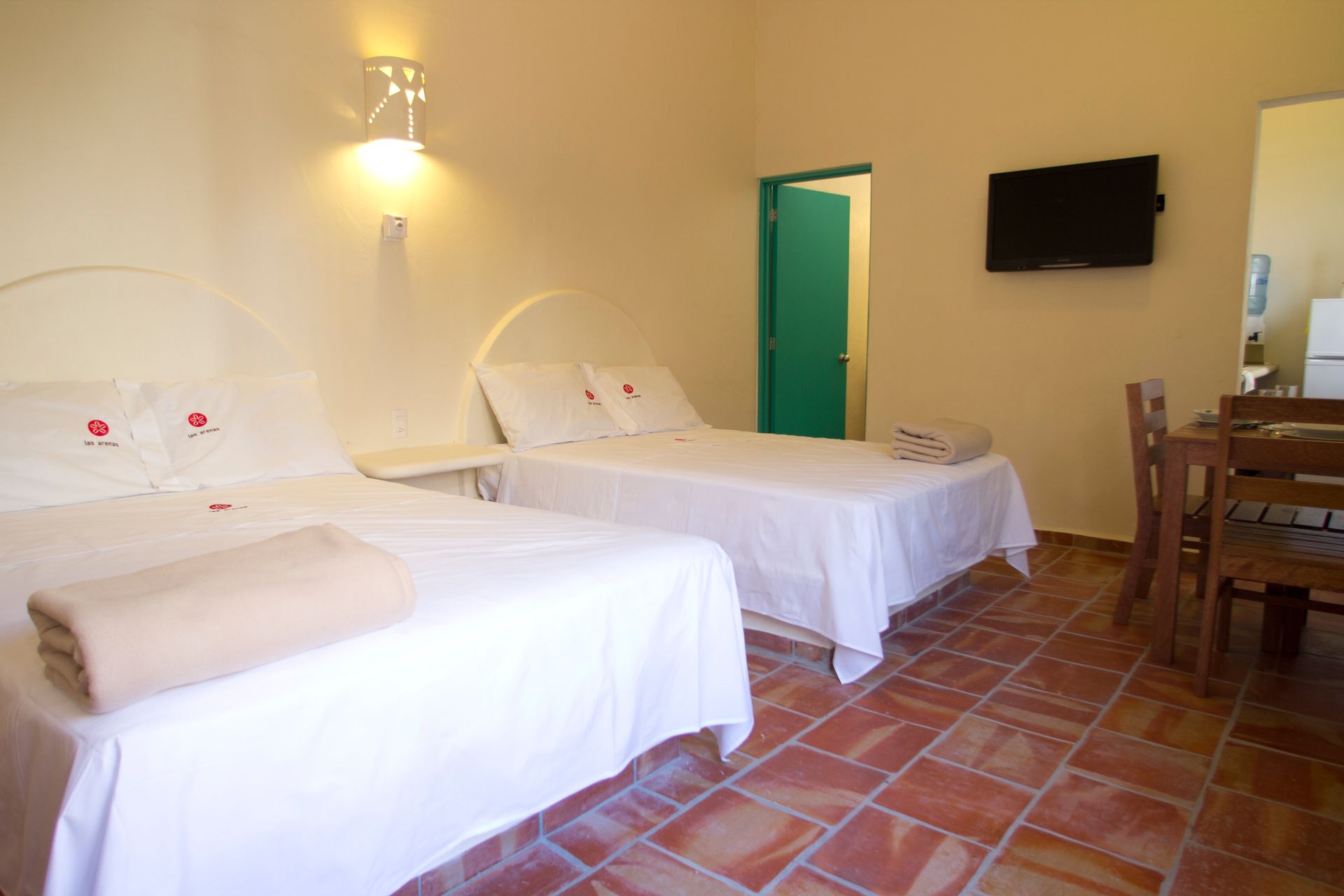A hotel room with two beds , a table and a television.