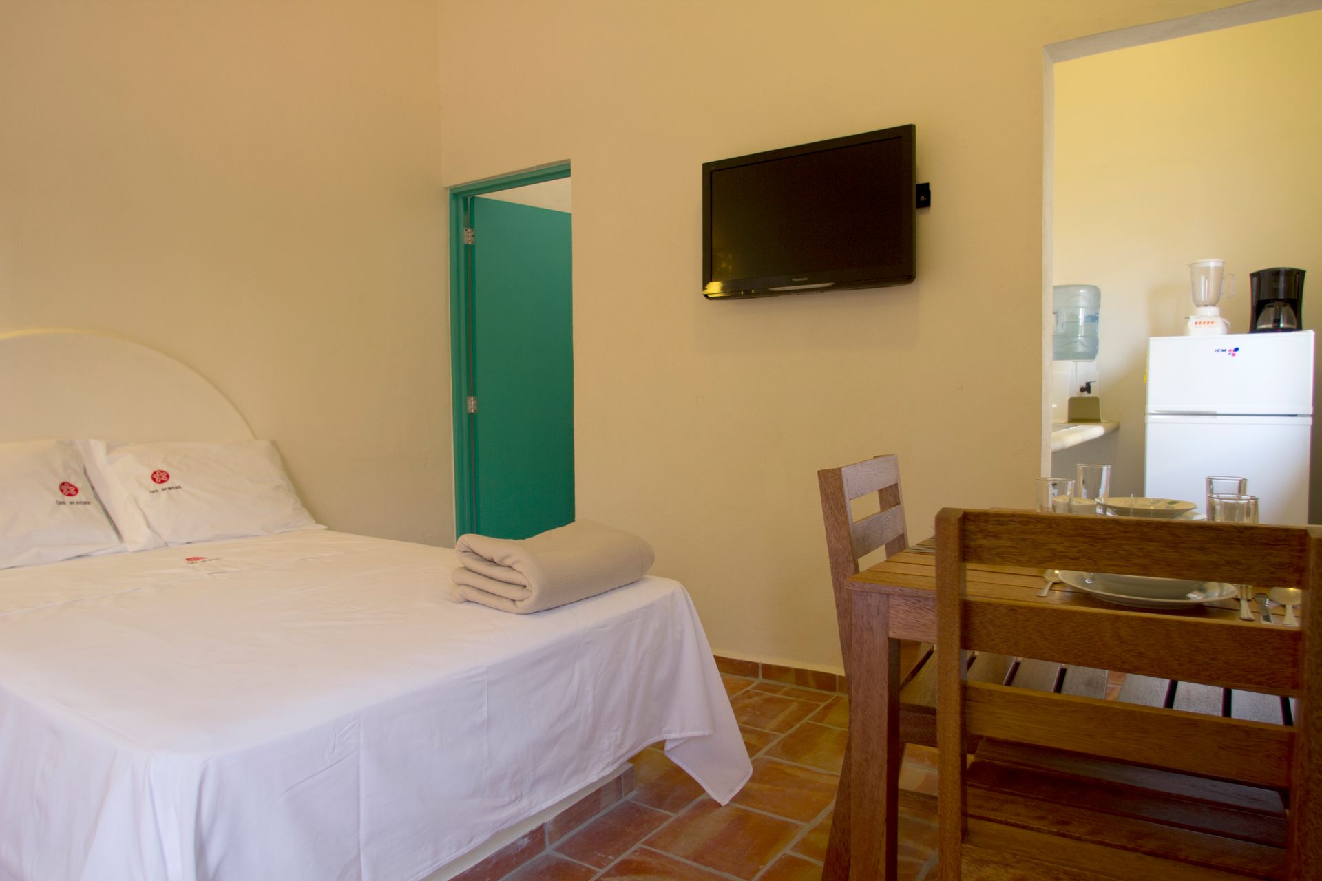 A bedroom with a bed , television , table and chairs.
