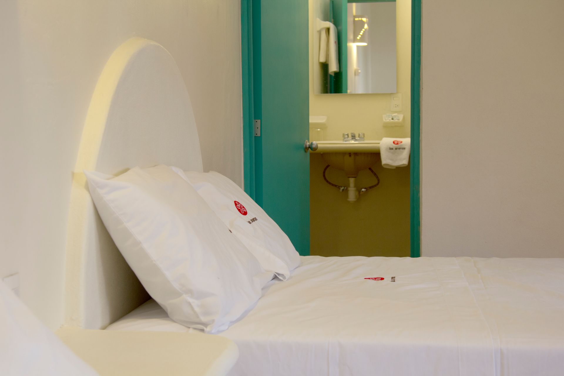 A bedroom with a bed and a bathroom in the background