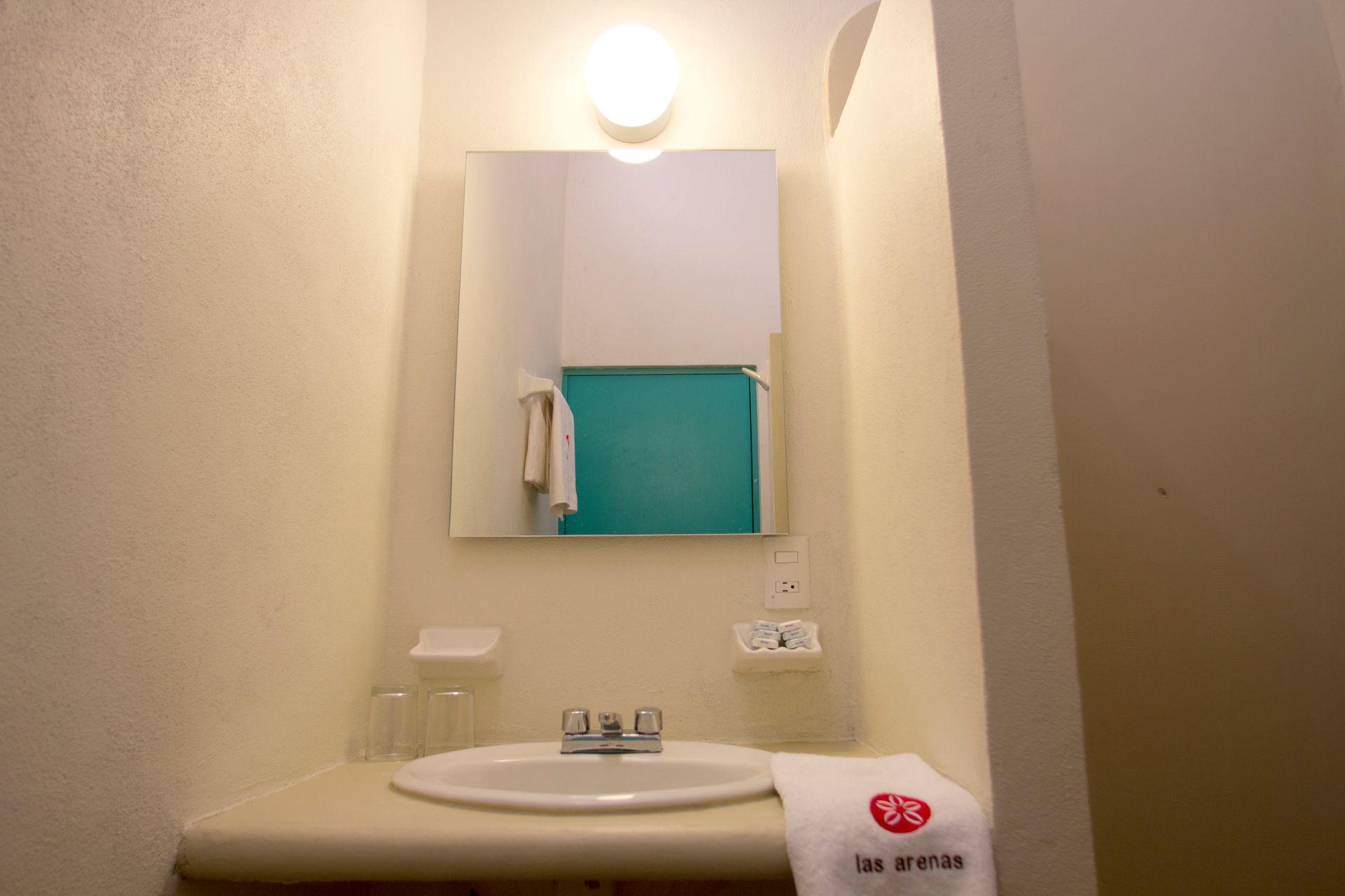 A bathroom with a sink , mirror and towel.