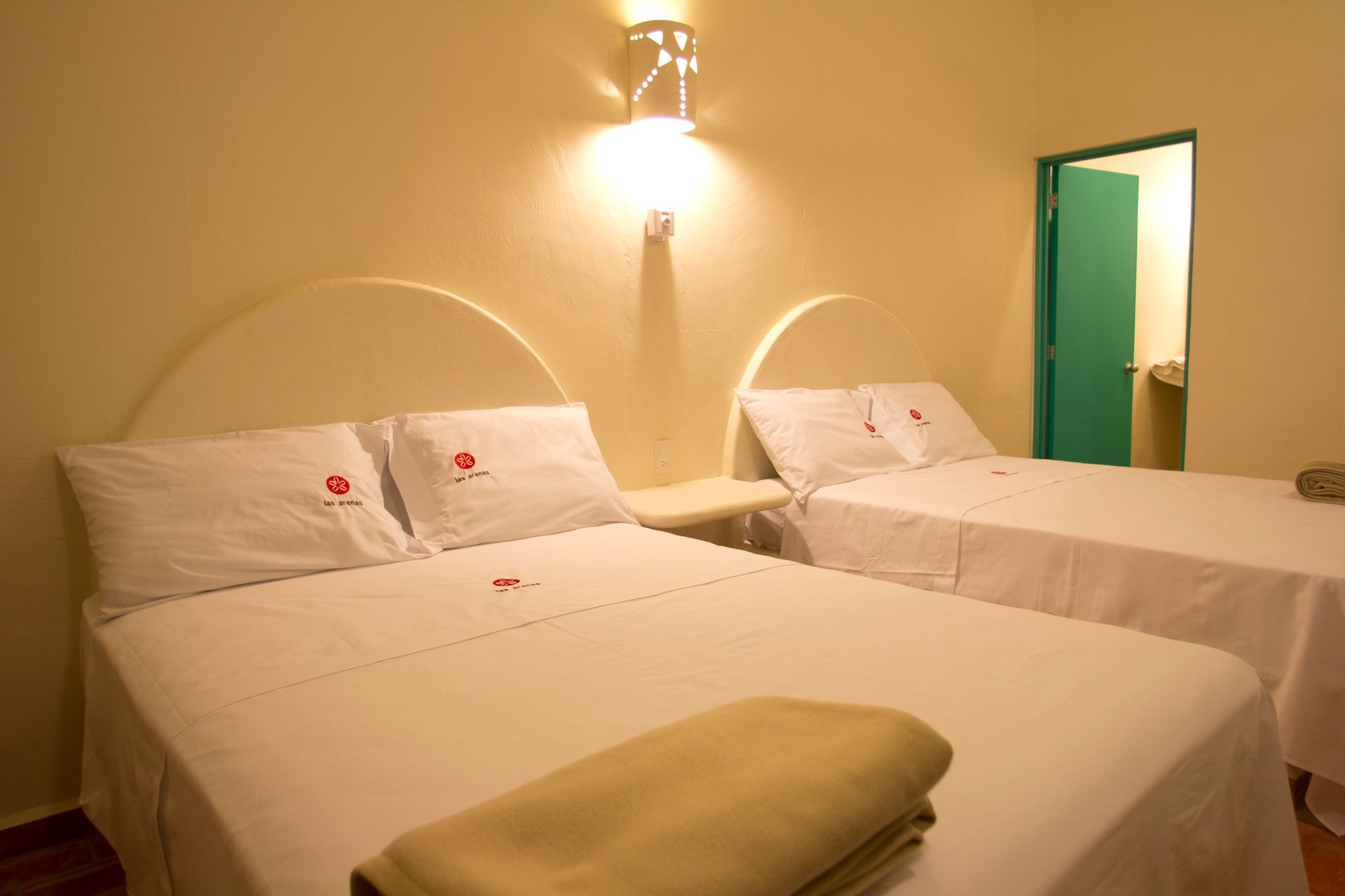 A hotel room with two beds and a green door