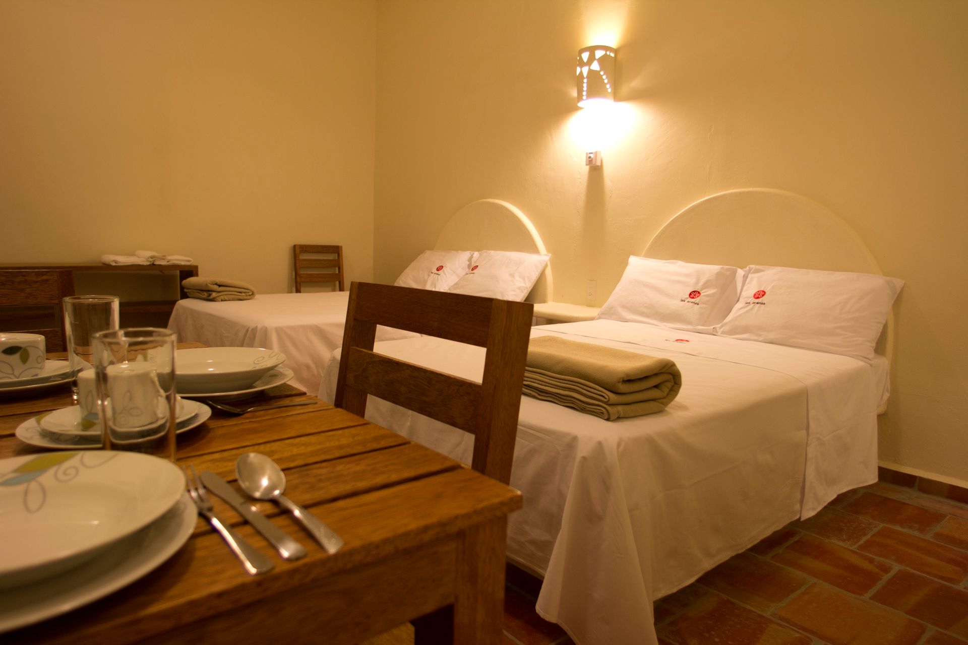 A hotel room with two beds and a table with plates and silverware