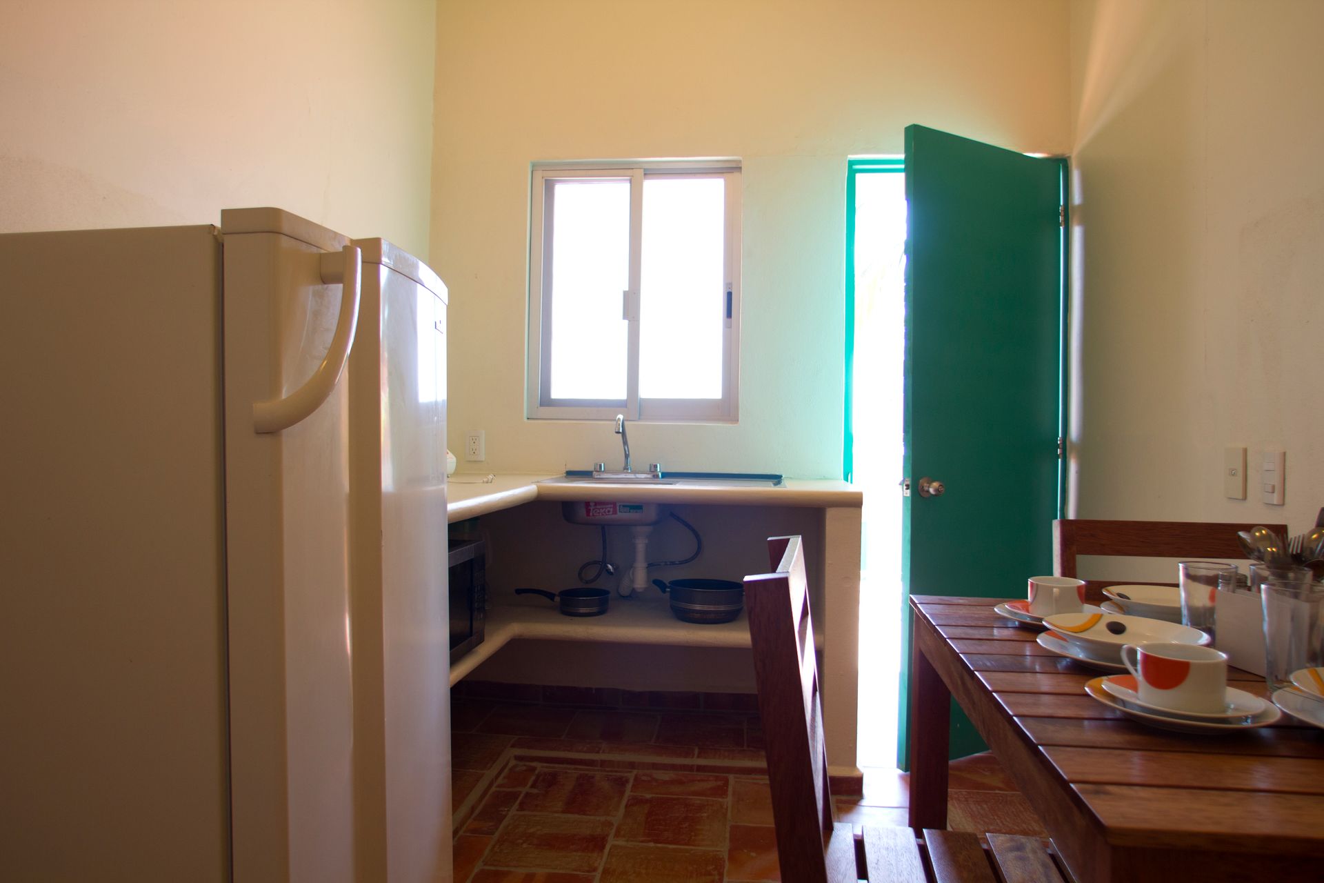 A kitchen with a table and chairs and a green door