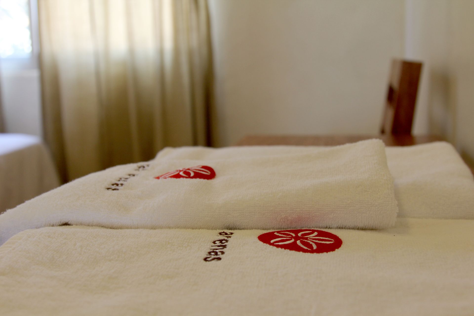 Two white towels are laying on a bed in a hotel room.