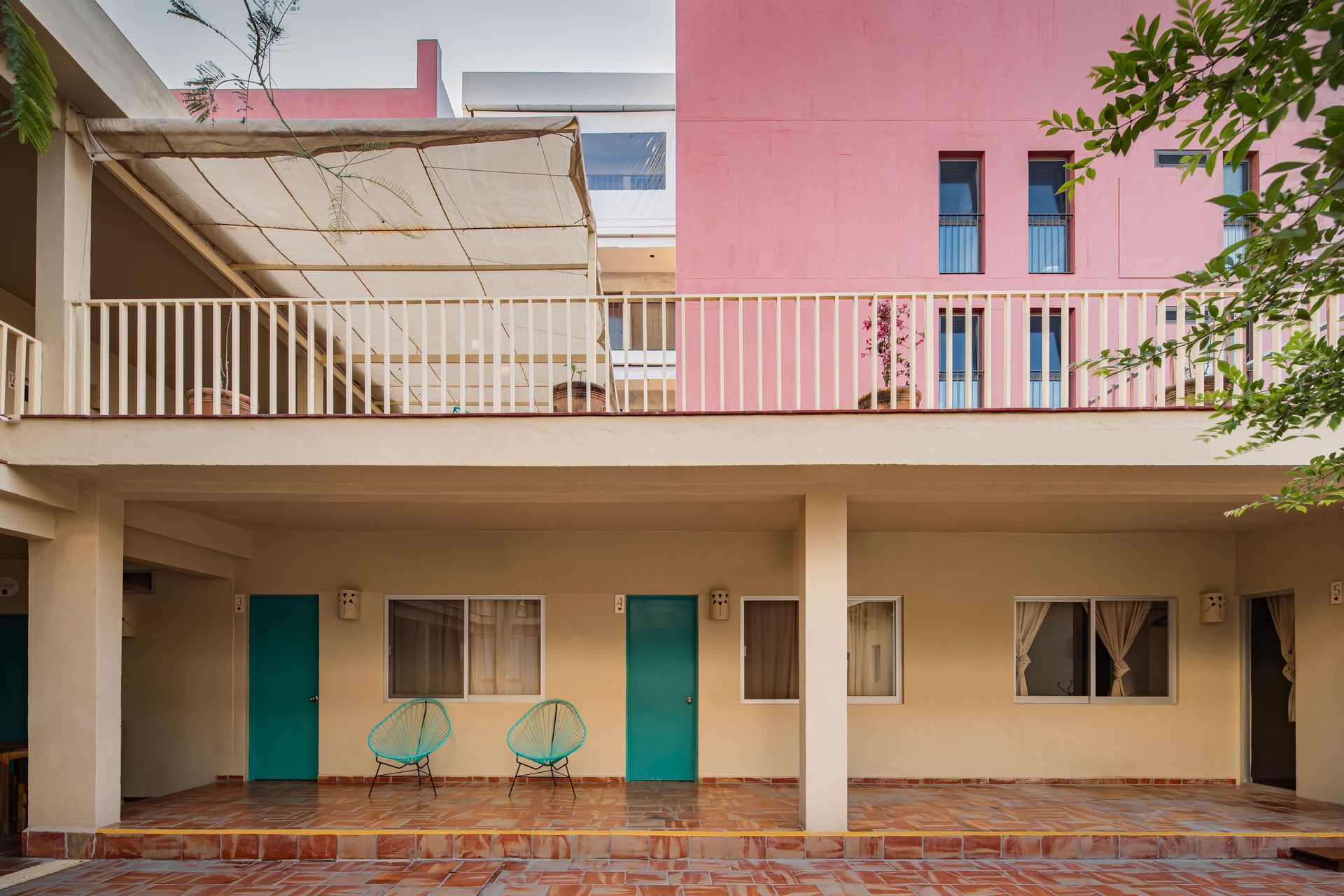 A pink building with a balcony and green doors