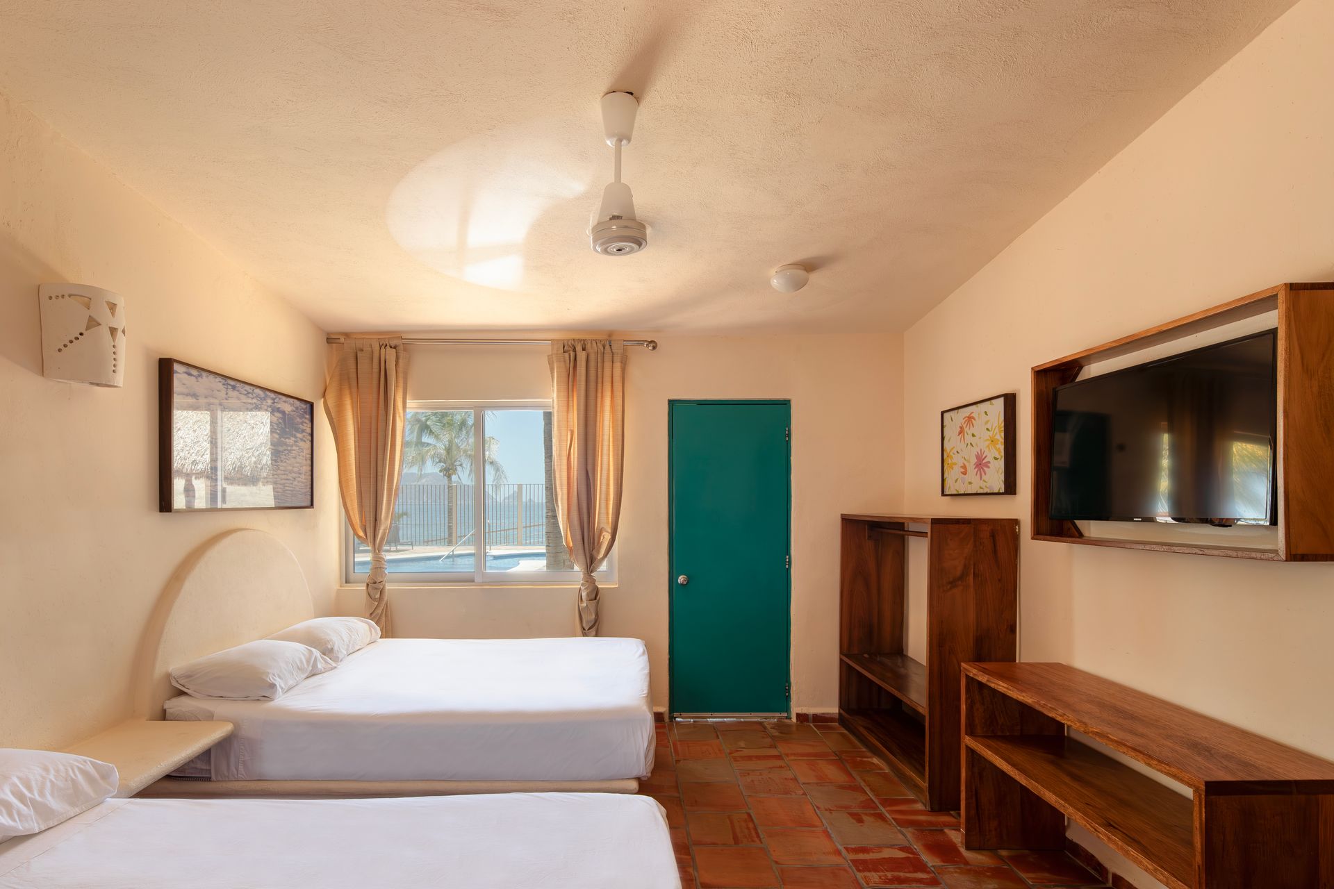 A hotel room with two beds , a television and a ceiling fan.