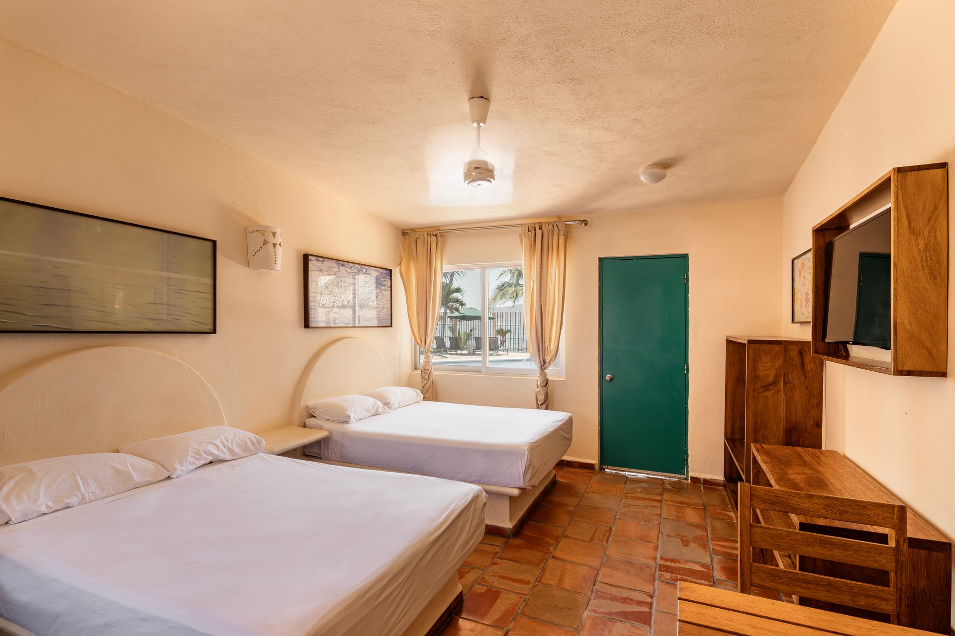 A hotel room with two beds , a desk and a television.