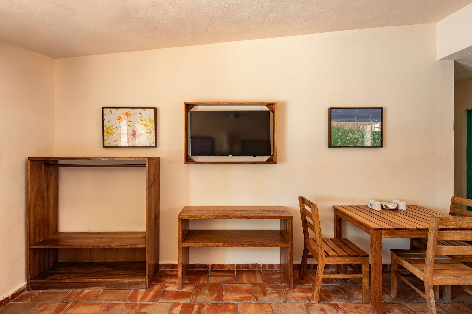 A living room with a table and chairs and a flat screen tv on the wall.