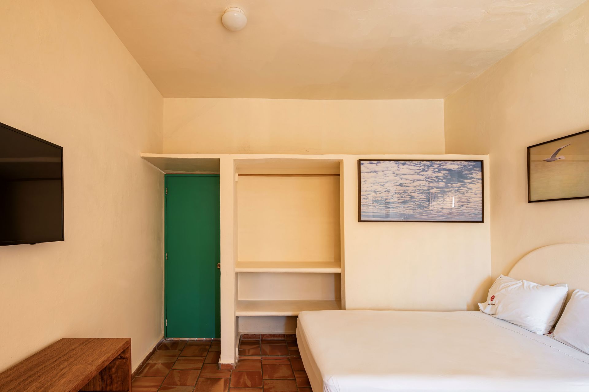 A hotel room with a bed , television , and a picture on the wall.