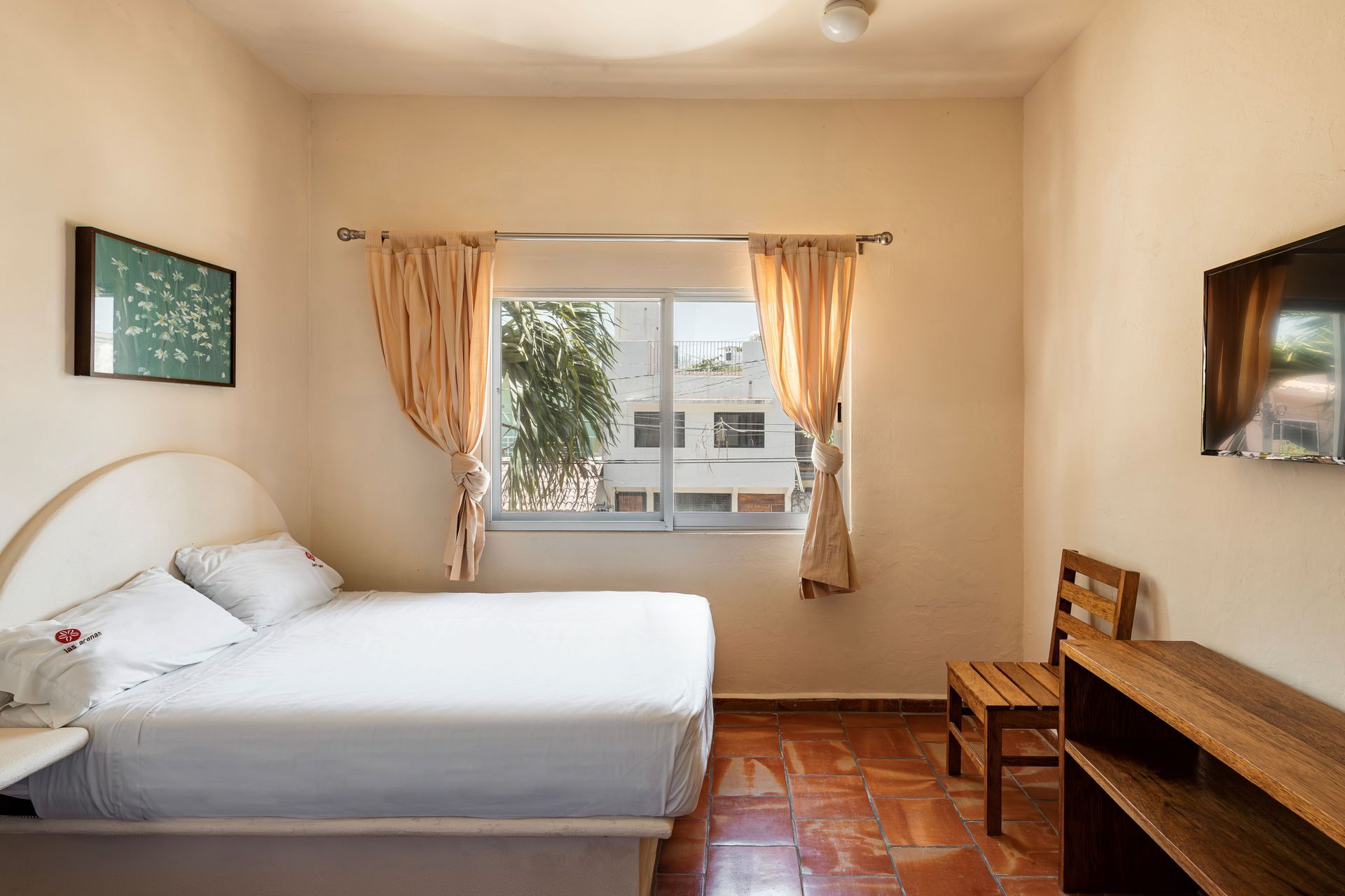 A hotel room with a bed , chair , television and window.
