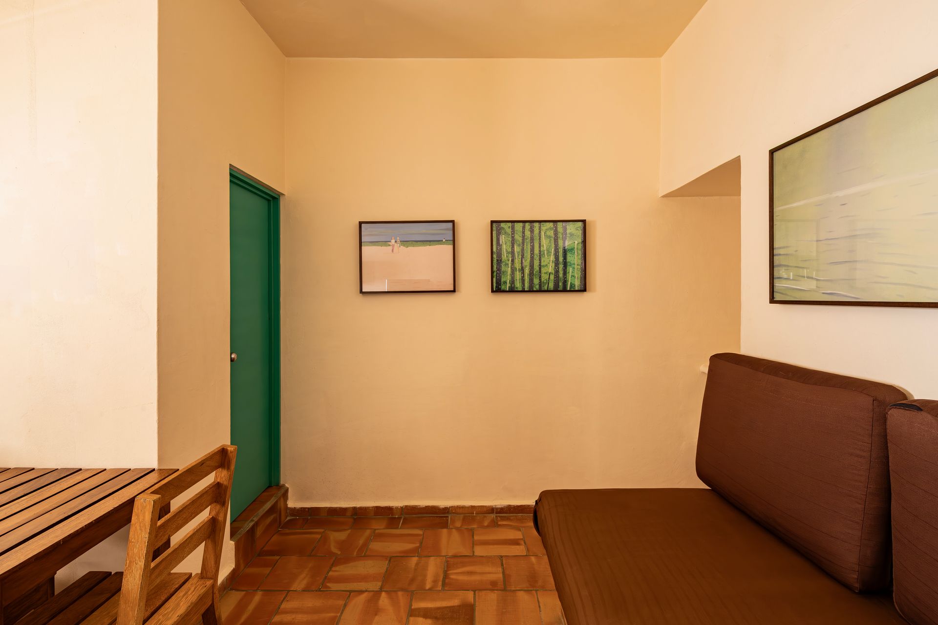 A living room with a couch , table and two paintings on the wall.