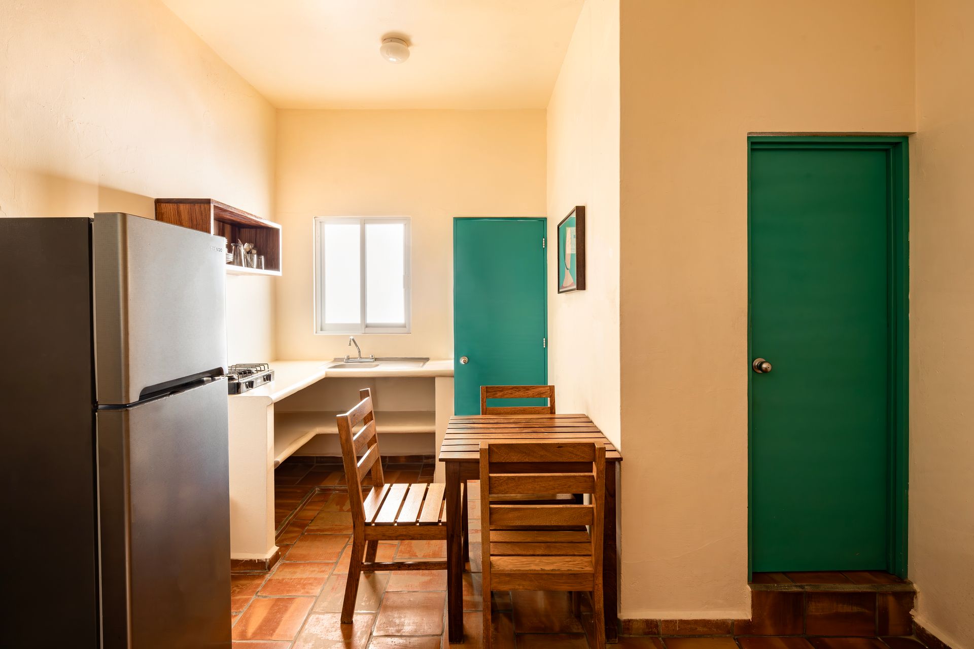 A kitchen with a table and chairs , a refrigerator , and a green door.