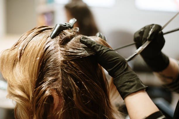 A woman is getting her hair dyed in a salon.