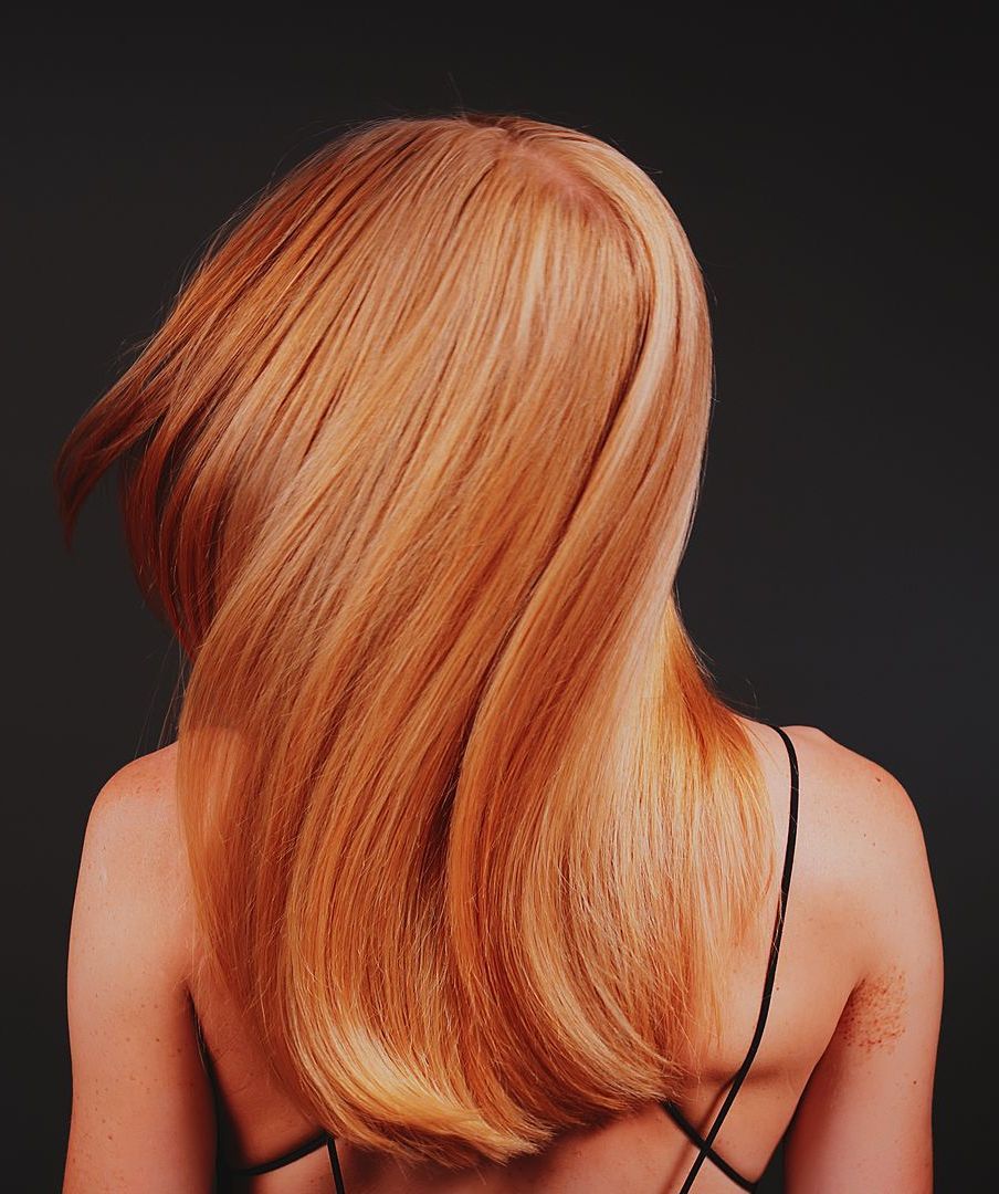 A woman with long red hair is wearing a black tank top