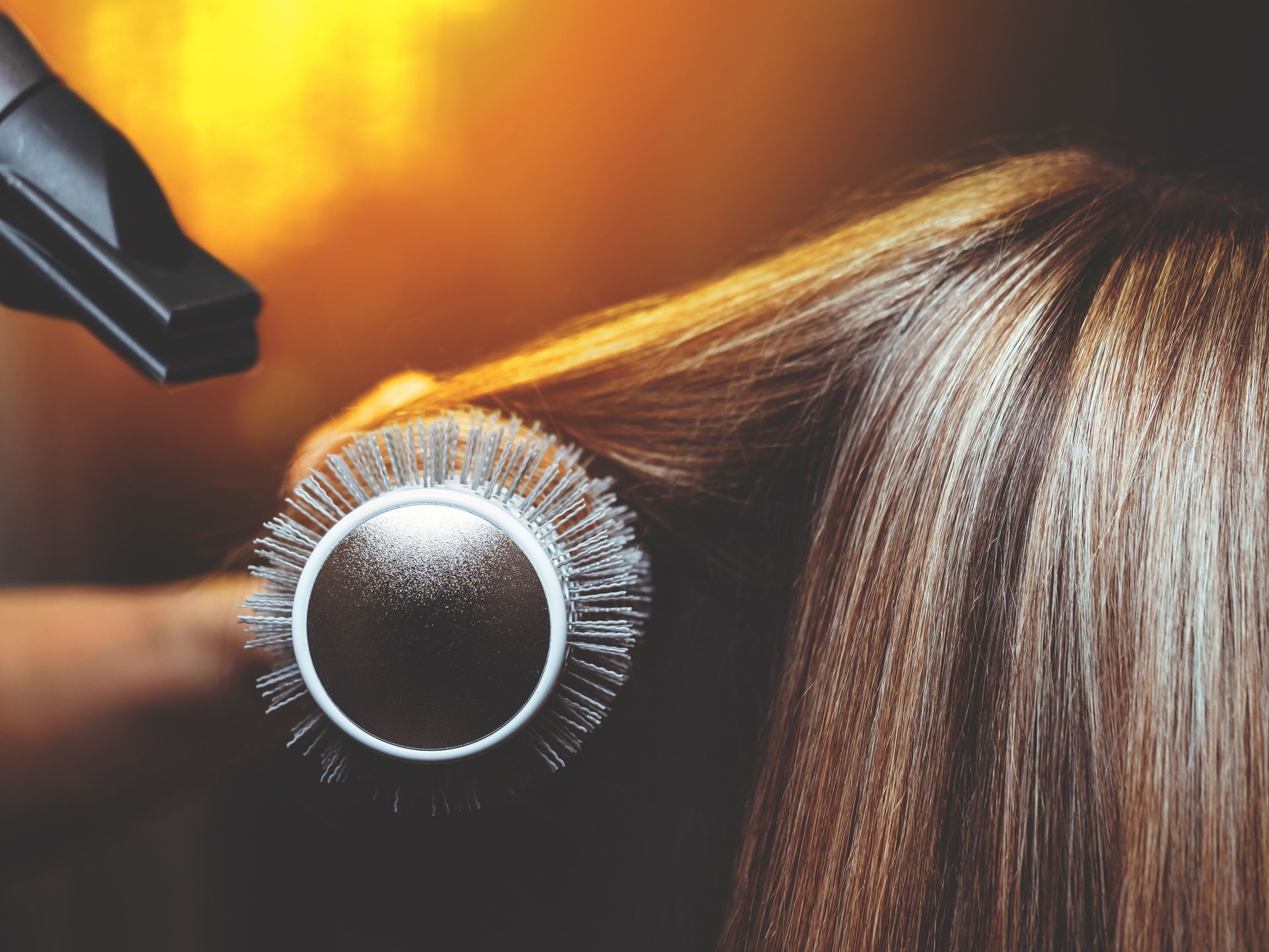 A woman is getting her hair blow dried with a brush