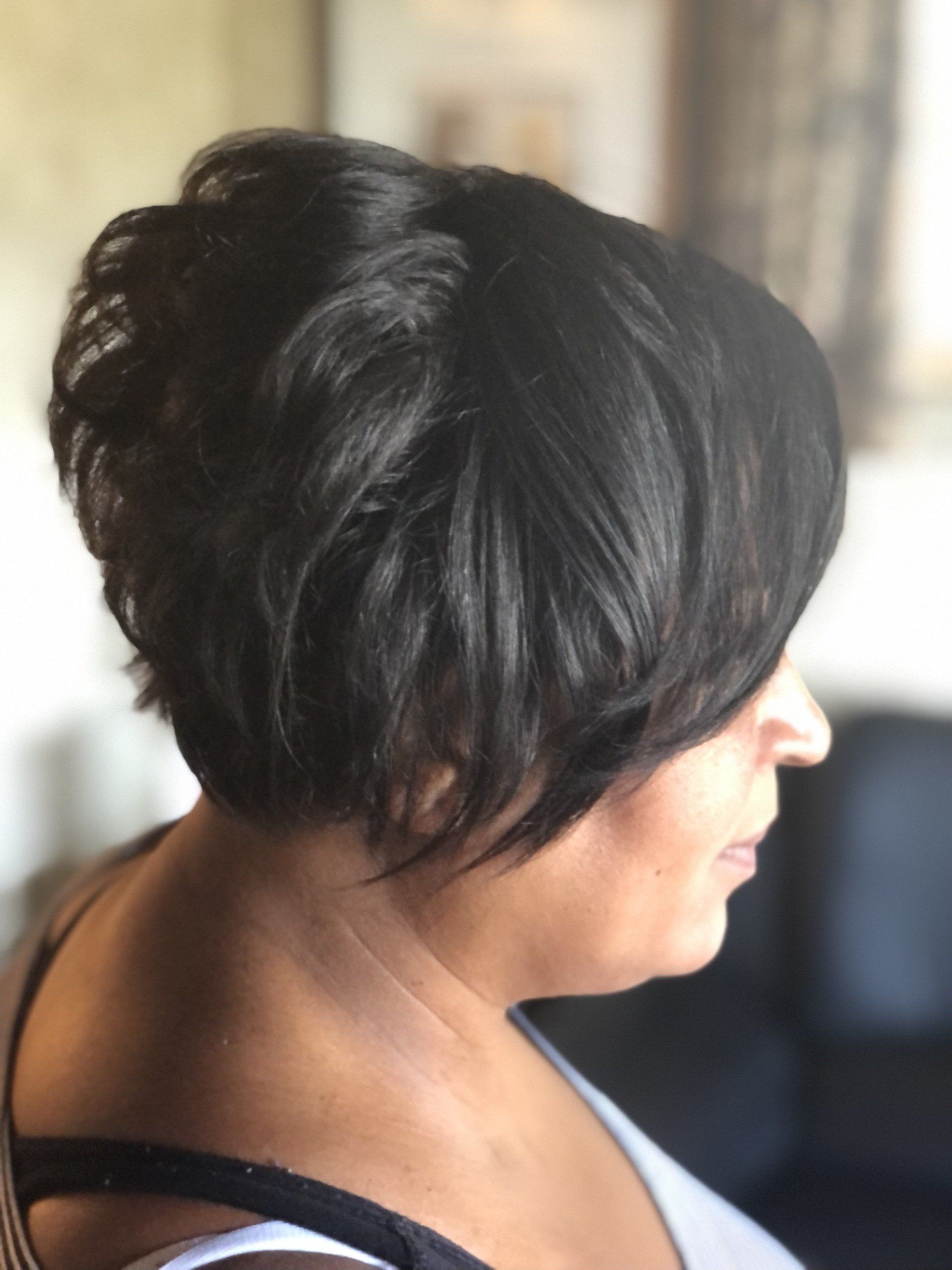 A woman with short black hair is sitting on a couch.
