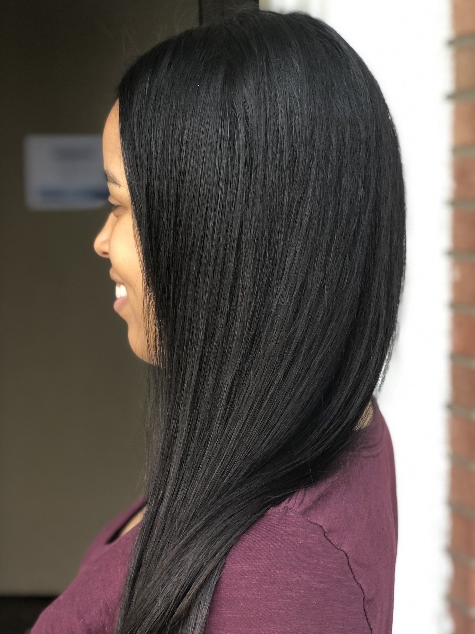 A woman with long black hair is wearing a purple shirt.