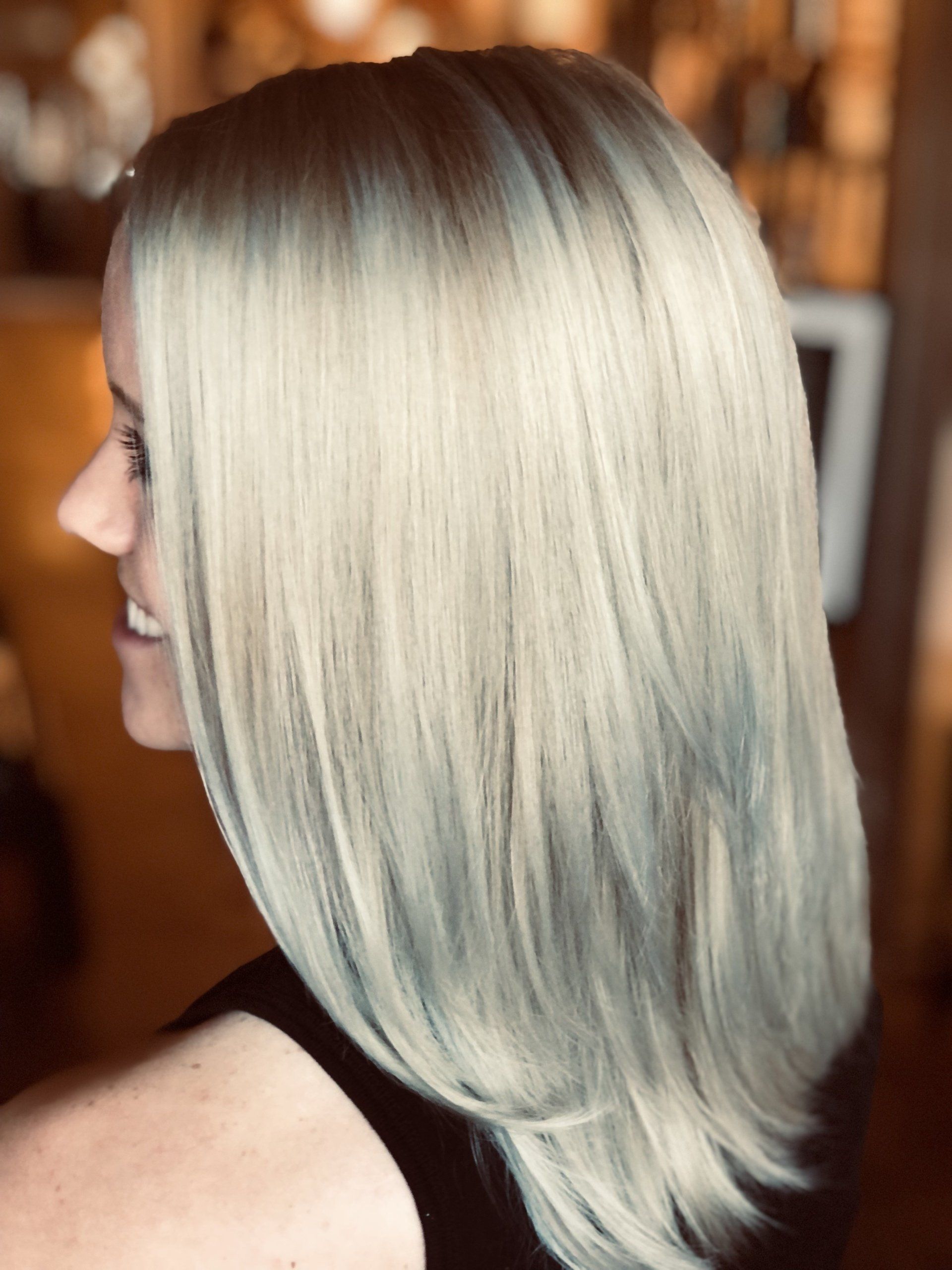 A woman with blonde hair is smiling and wearing a black shirt.