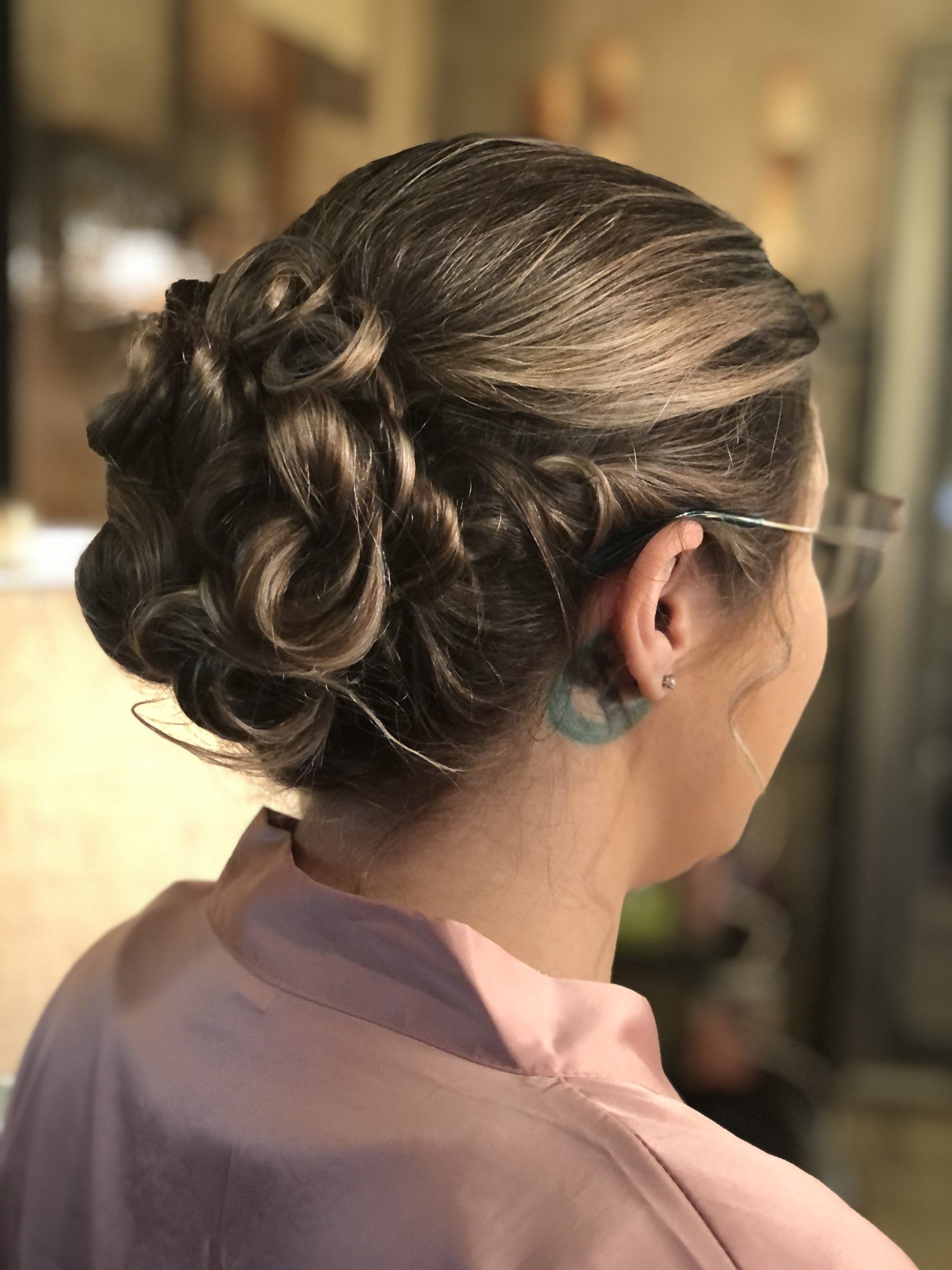 A woman is wearing a pink robe and has her hair in a bun.