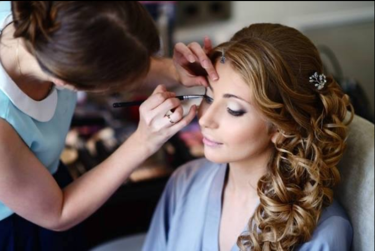 A woman is getting her makeup done by a makeup artist