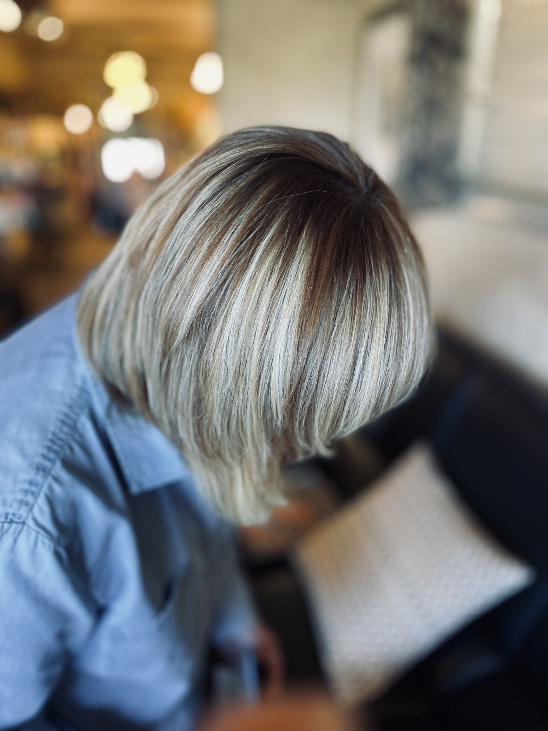 A woman with blonde hair is looking down at her hair.