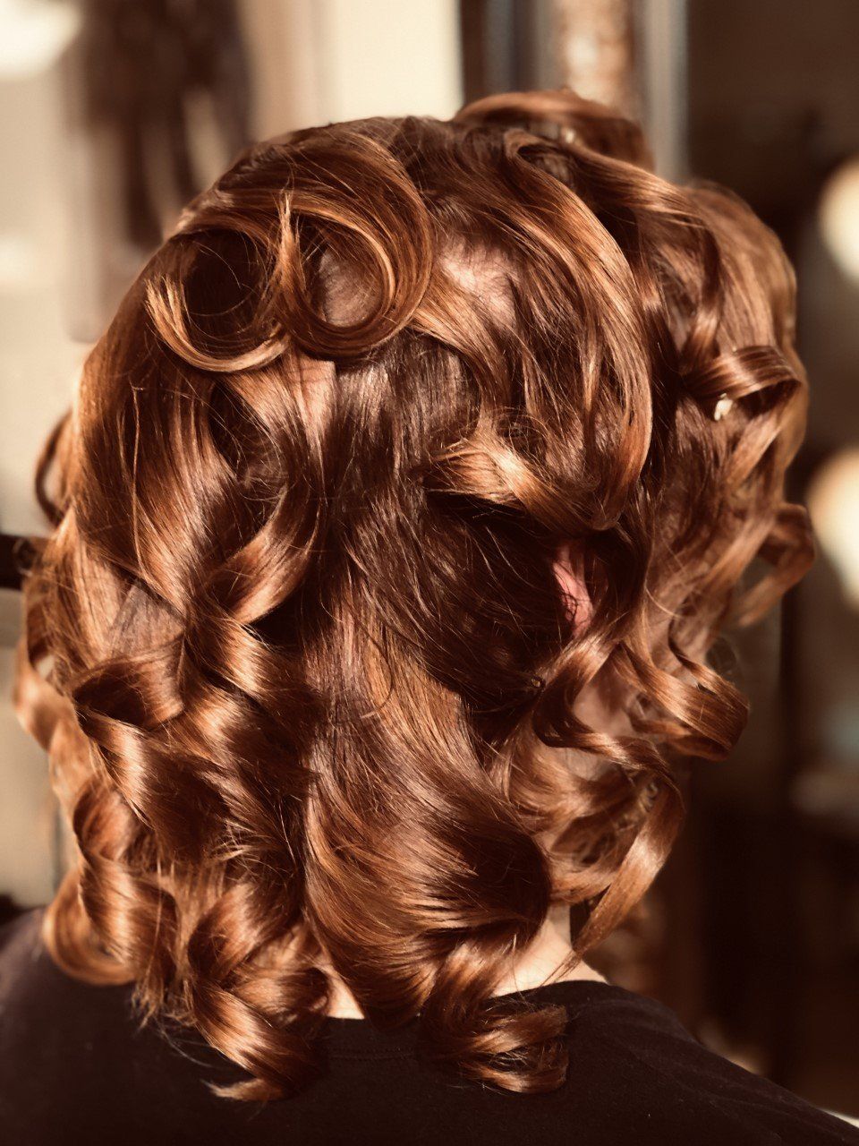A close up of a woman 's hair with curls in a bun.