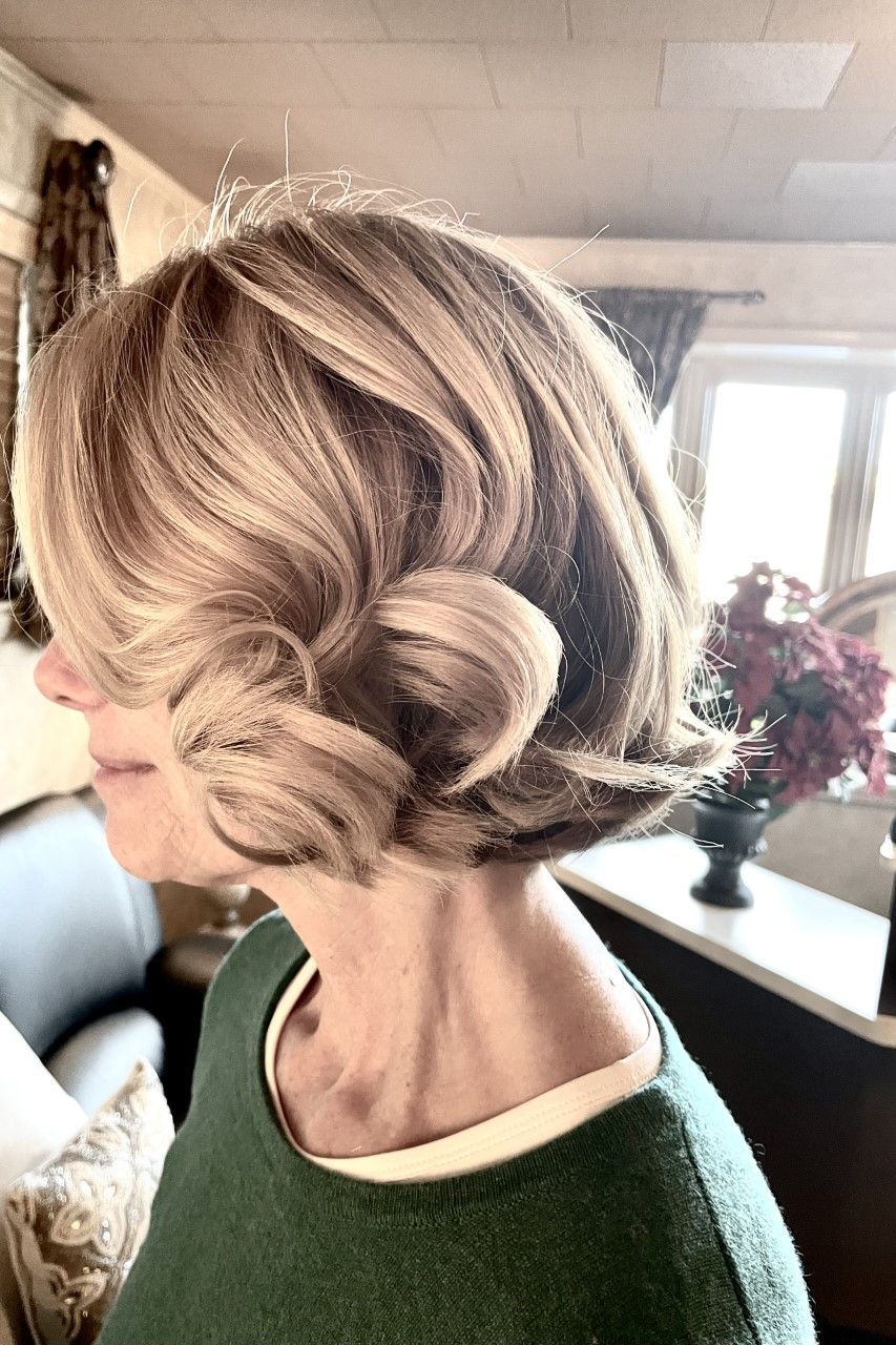 A woman with short blonde hair is wearing a green sweater.