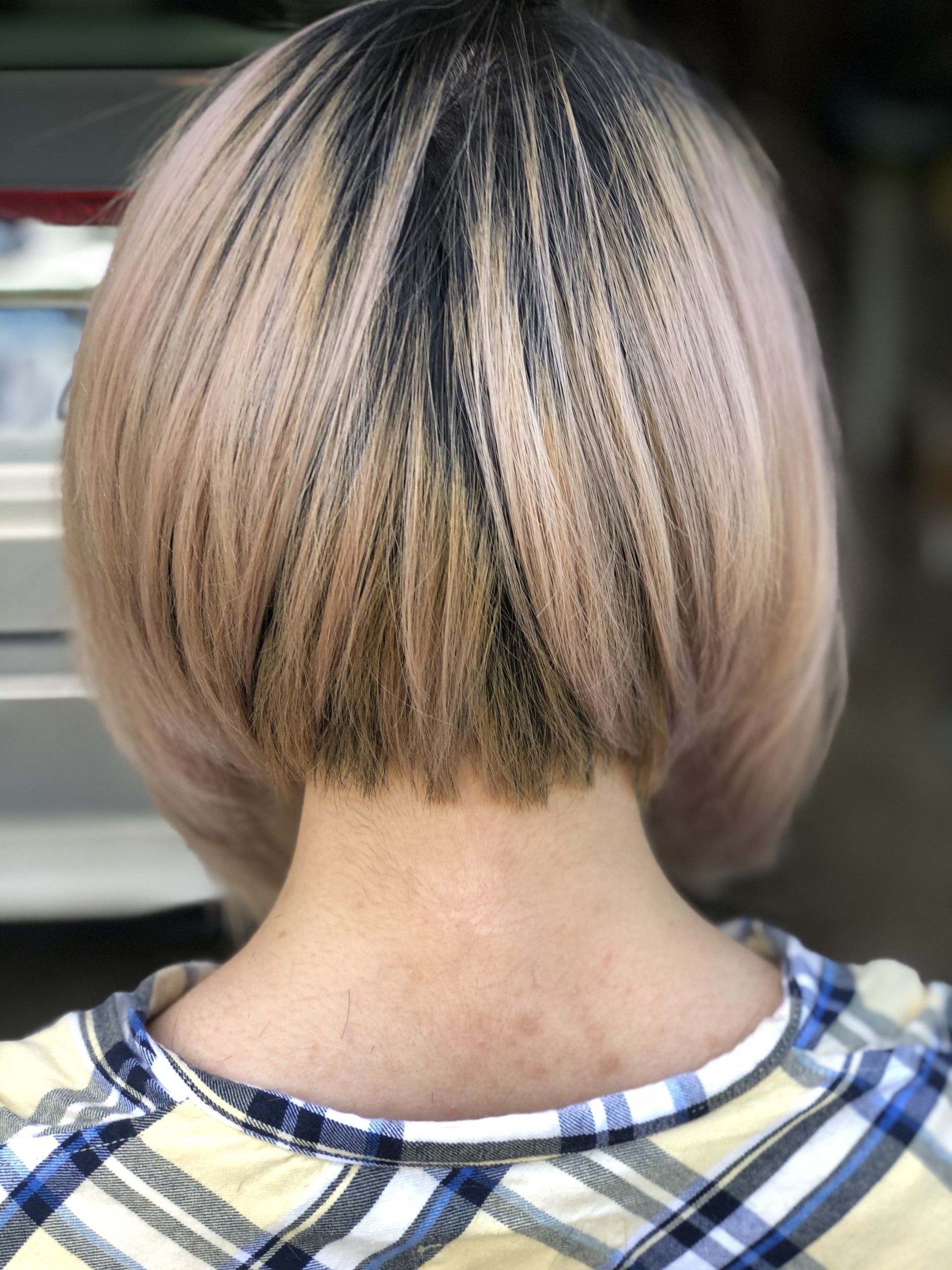 A woman with short blonde hair is wearing a plaid shirt.