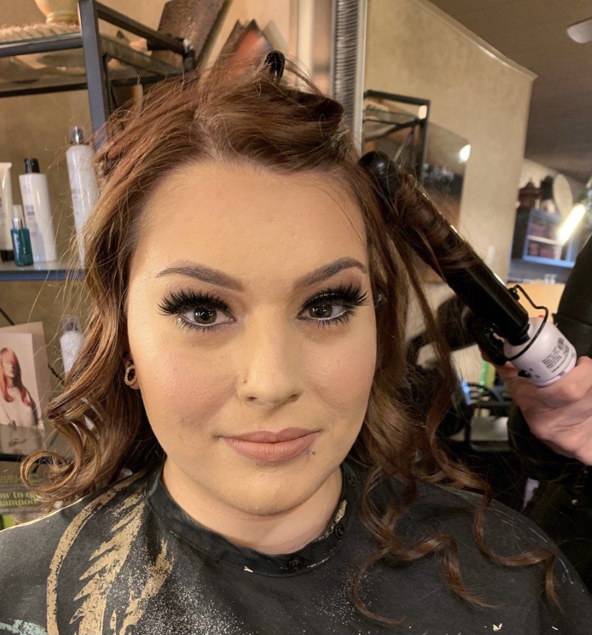 A woman is getting her hair curled in a salon