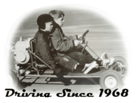 Two boys are driving a go kart with the words driving since 1968 below them