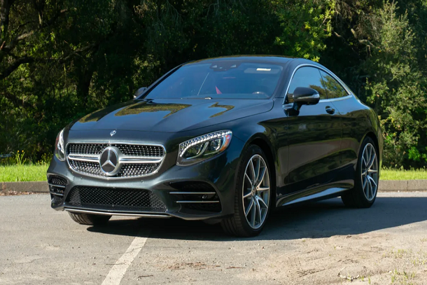 A black mercedes benz s class coupe is parked on the side of the road.