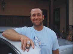 A man in a blue shirt is standing next to a car.