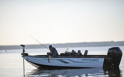 A man is fishing in a boat on a lake.