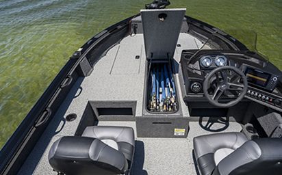 The front of a fishing boat with a steering wheel and a storage box filled with fishing rods.