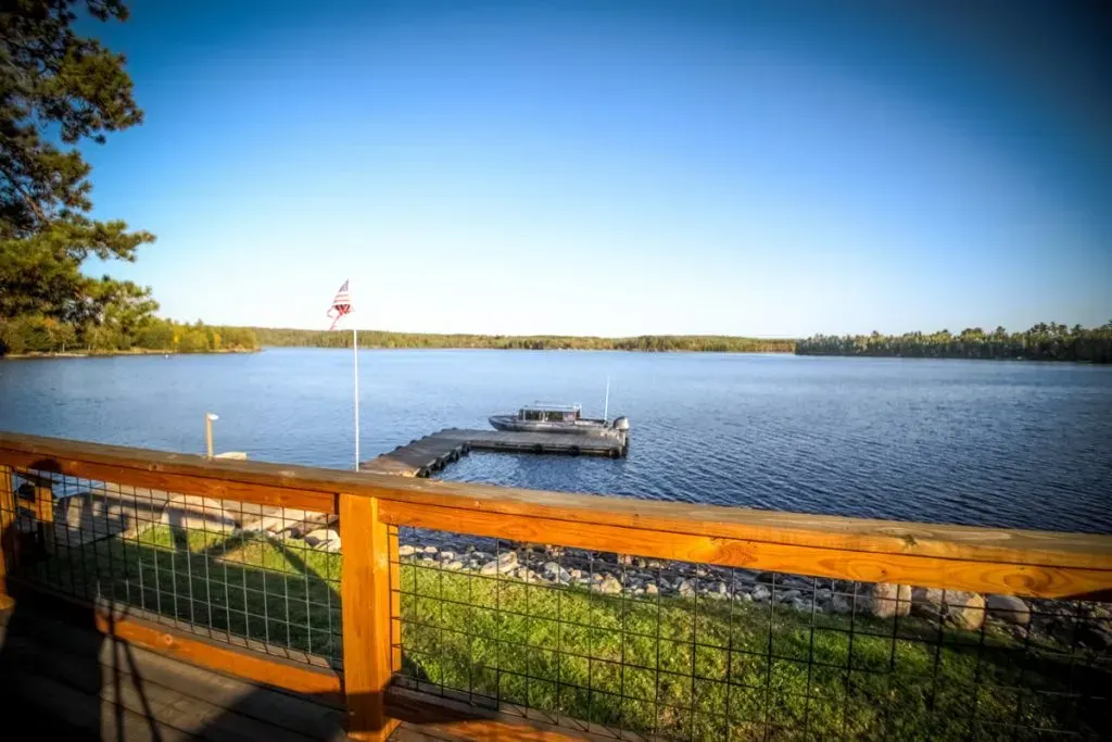 A view of a lake from a deck with a boat docked in the water.