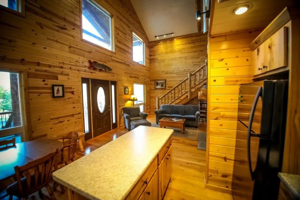 A kitchen in a log cabin with a large island and a refrigerator.