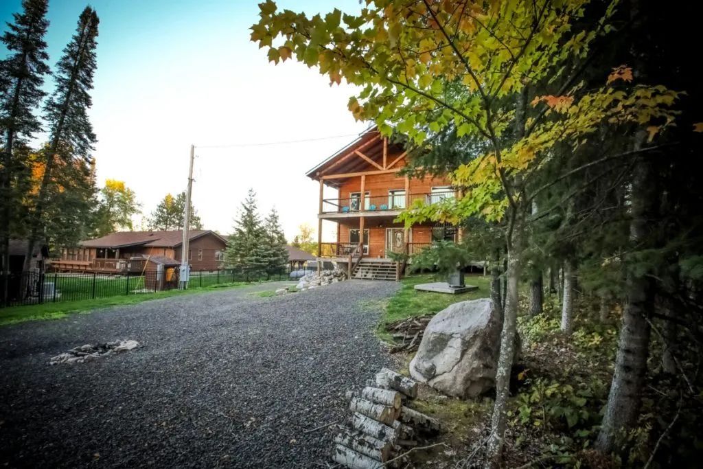 A large house is surrounded by trees and gravel