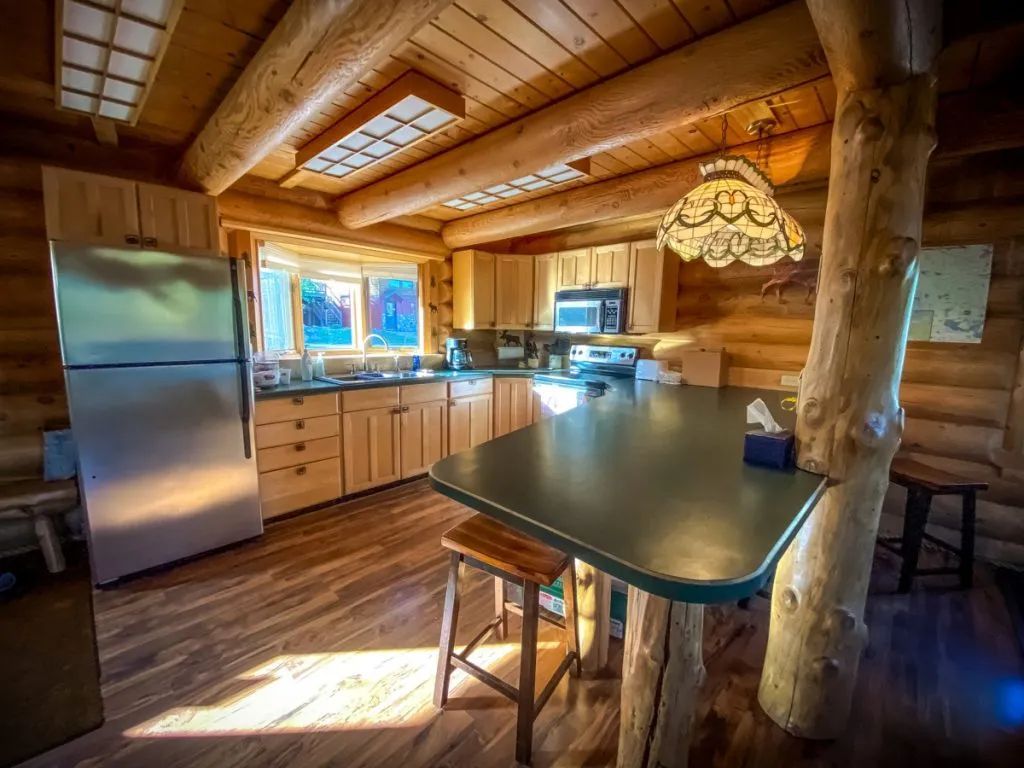 A kitchen in a log cabin with stainless steel appliances and a large island.