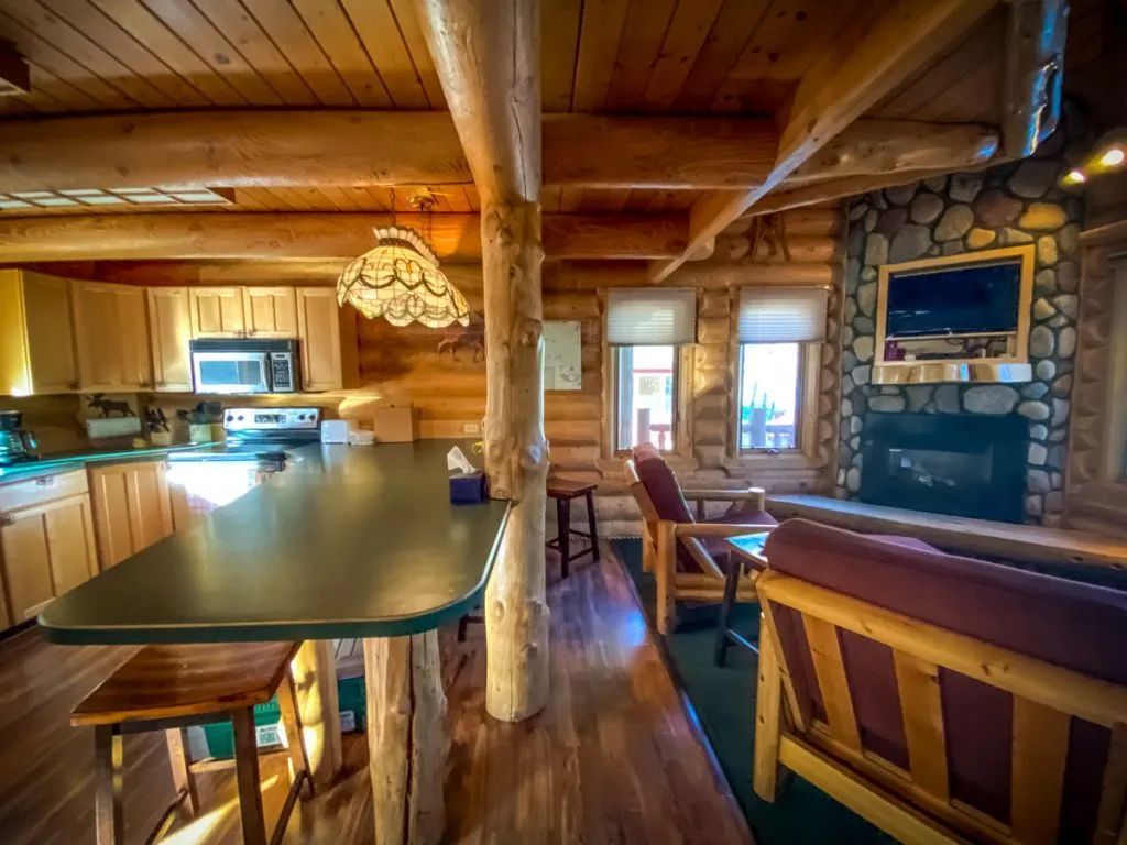 A log cabin with a kitchen , living room , and fireplace.