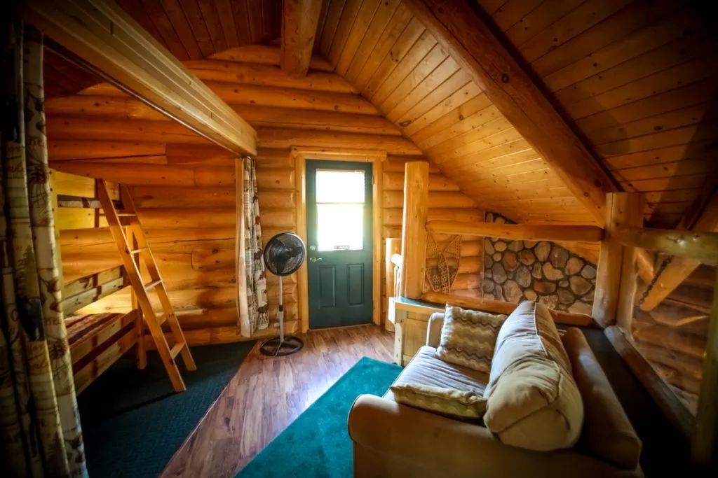 A living room in a log cabin with a couch and bunk beds