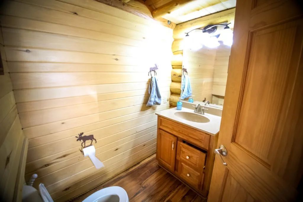 A bathroom in a log cabin with a toilet , sink and mirror.