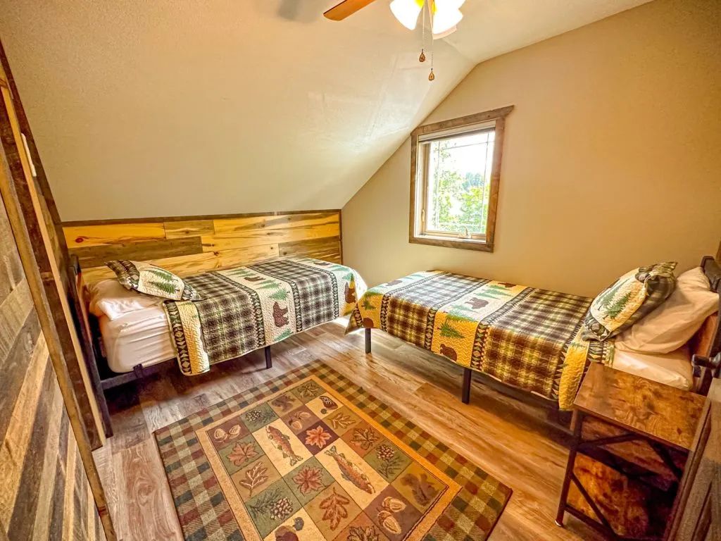 A bedroom with two beds , a rug and a ceiling fan.