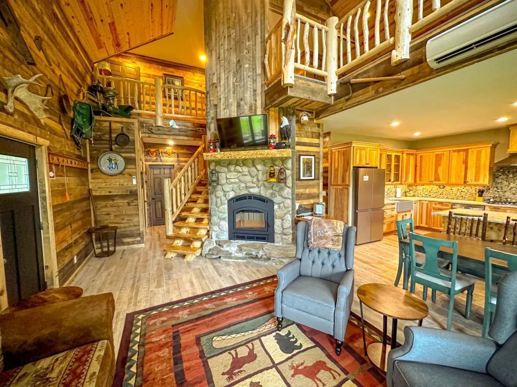 A living room in a log cabin with a fireplace and chairs.