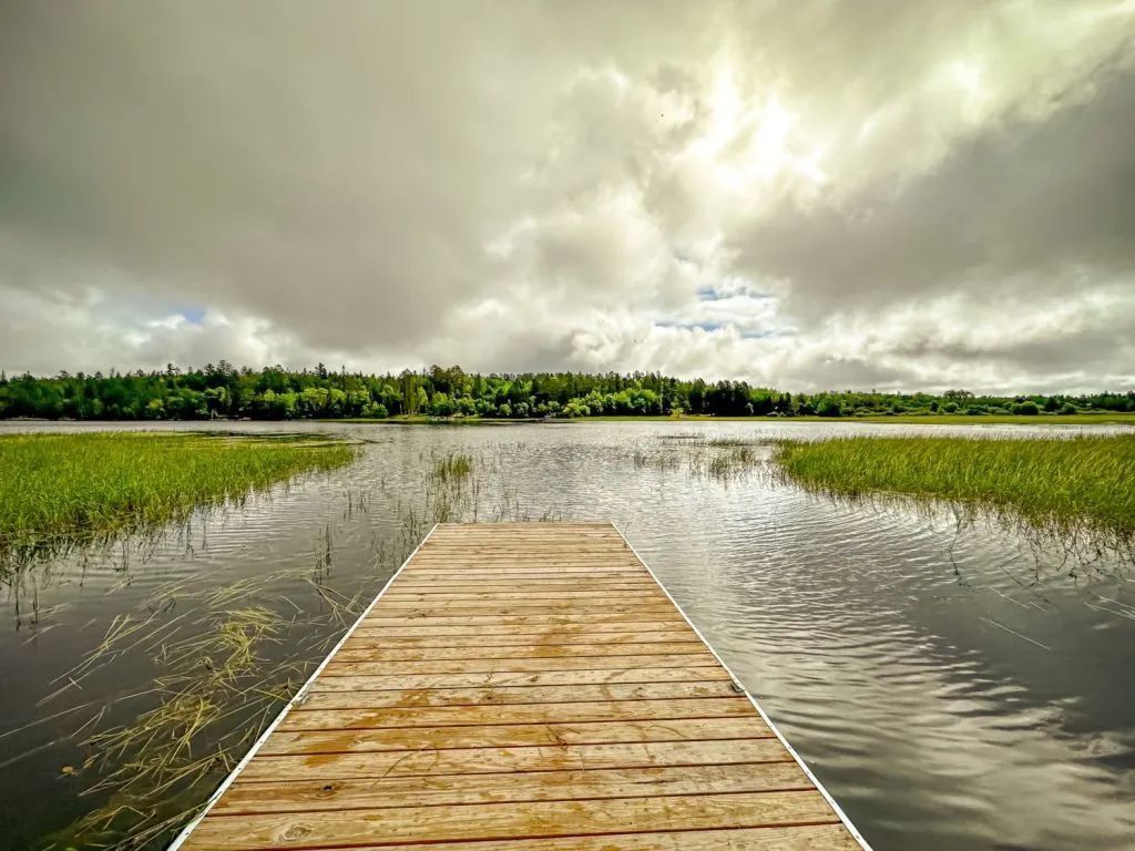 A wooden dock leading into a lake on a cloudy day.