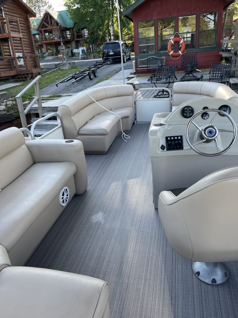 The inside of a pontoon boat with a steering wheel and a couch.