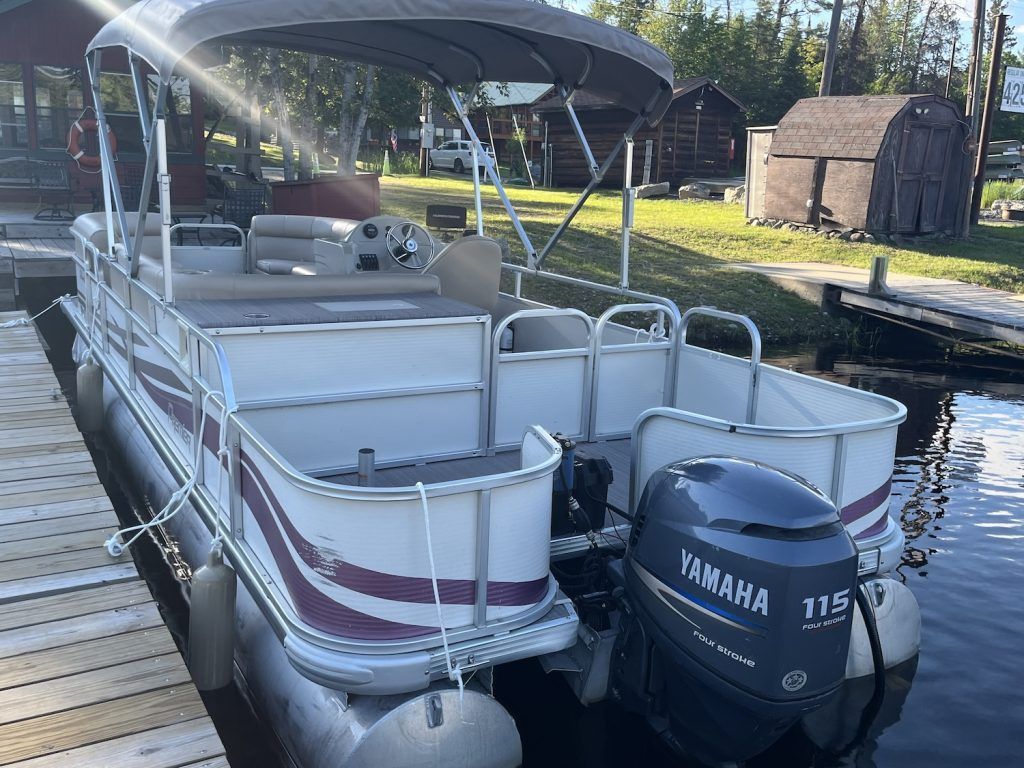 A pontoon boat with a yamaha engine is docked at a dock.