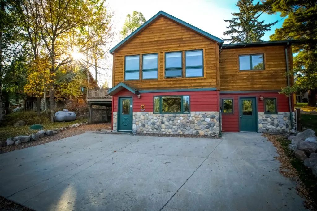 A large wooden house with a concrete driveway in front of it