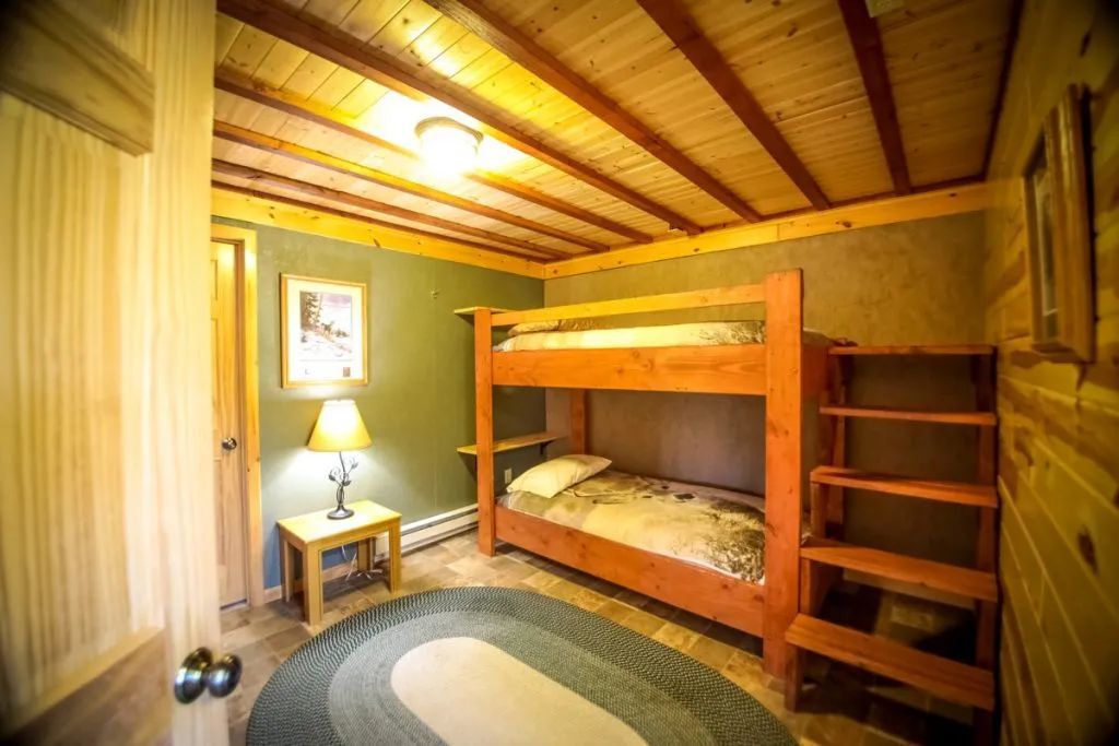 A bedroom with bunk beds and stairs in a log cabin.